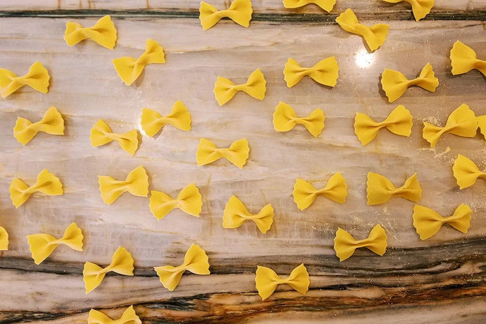Handmade bow-shaped pasta on a wooden surface by Pastaria Vivi