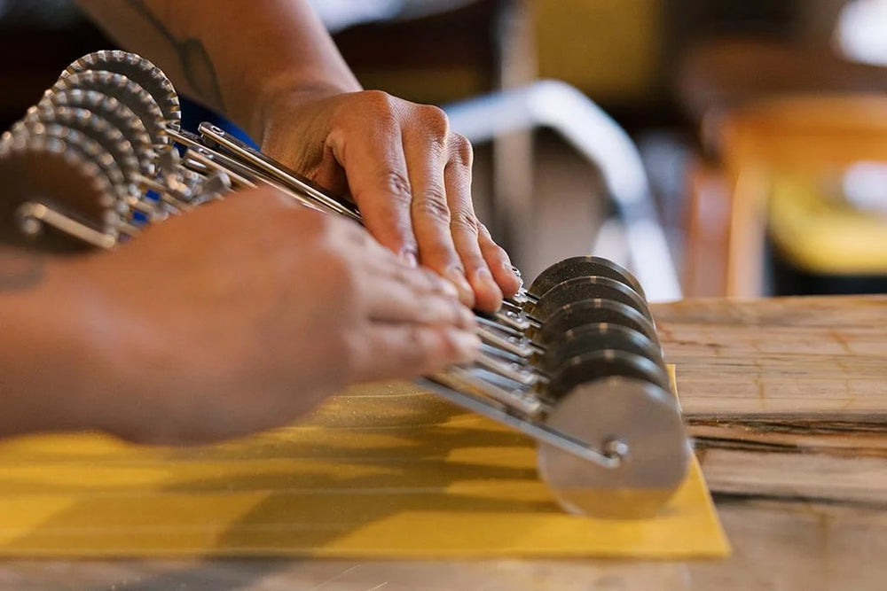 Person using a metal tool on a yellow surface with a blurred background