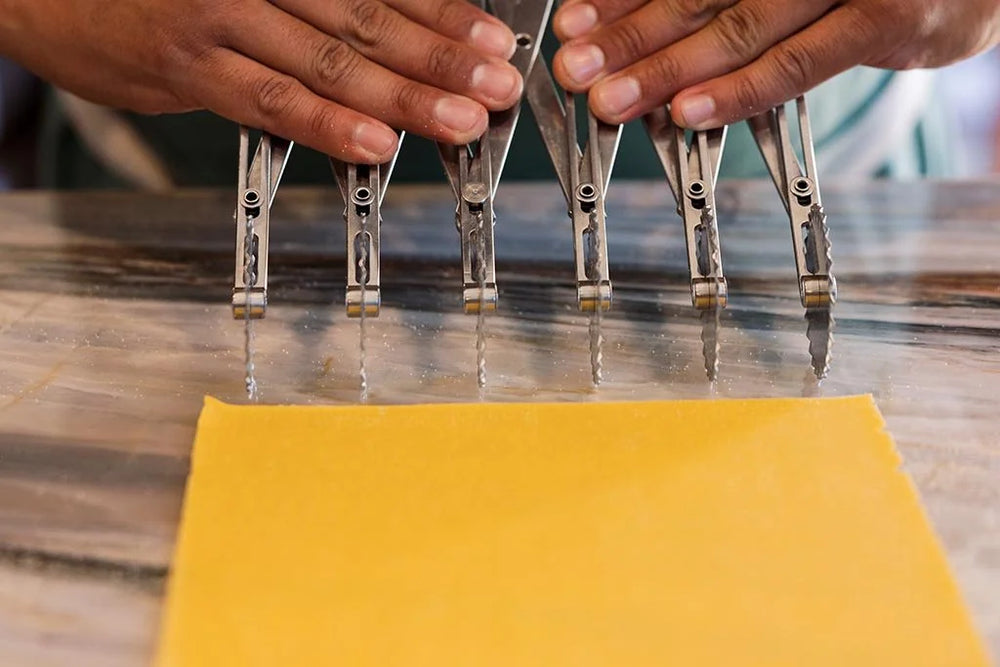 Chef cutting a yellow sheet of fresh handmade pasta