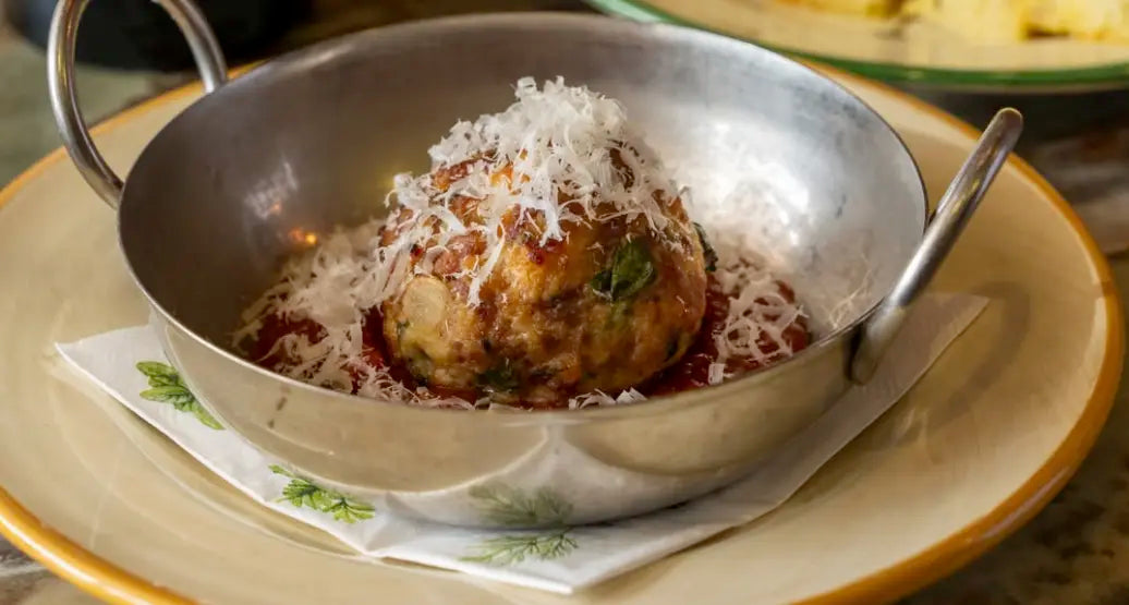 Dish with a meatball and sauce in a metal bowl on a table